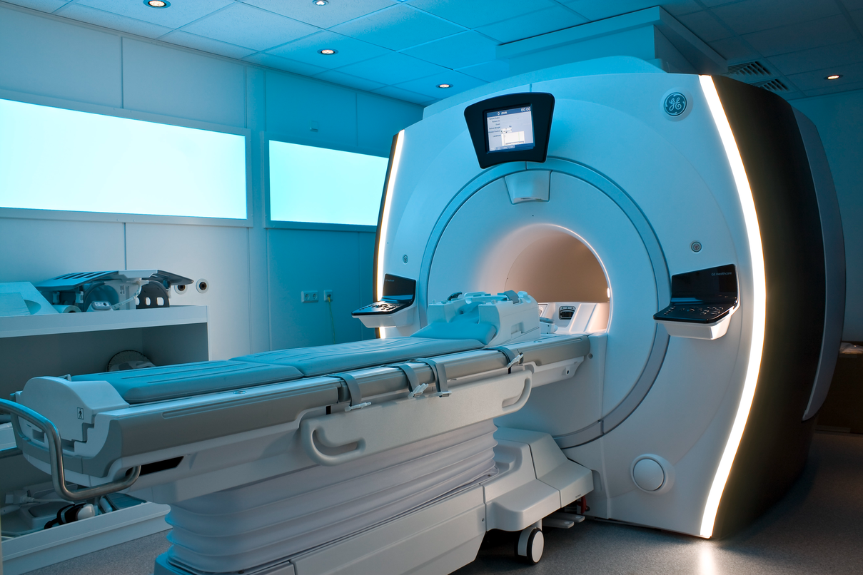 MRI machine with patient bed in a medical facility with blue-lit walls and control monitors