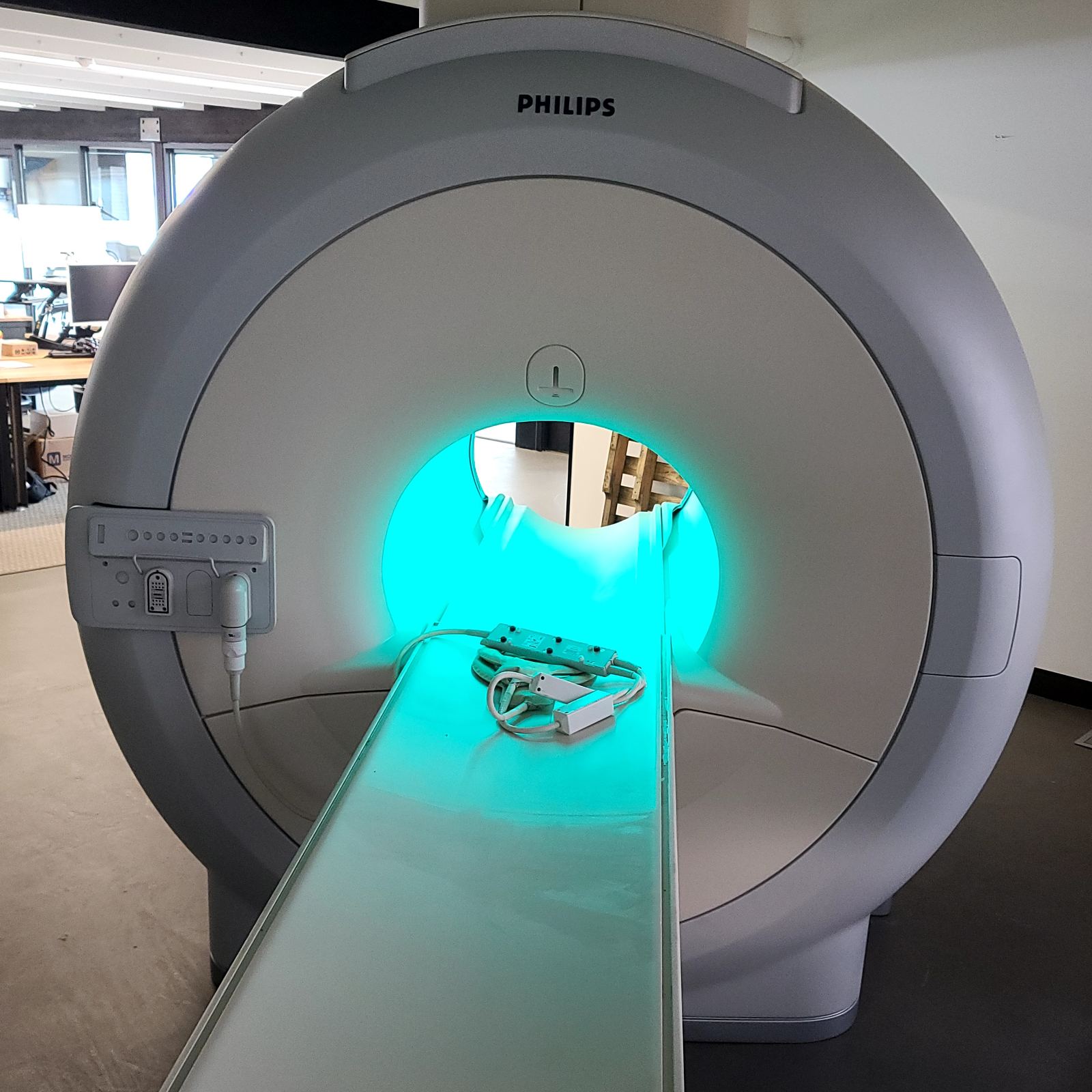 Philips MRI scanner with illuminated teal bore light and empty patient table, ready for service