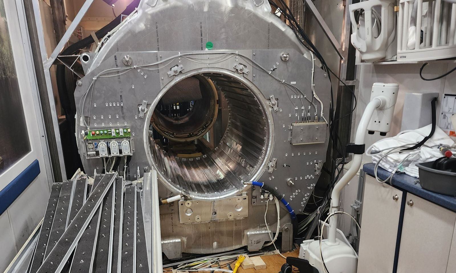 Open Philips MRI gantry mid-teardown with internal components exposed and tools scattered on the floor
